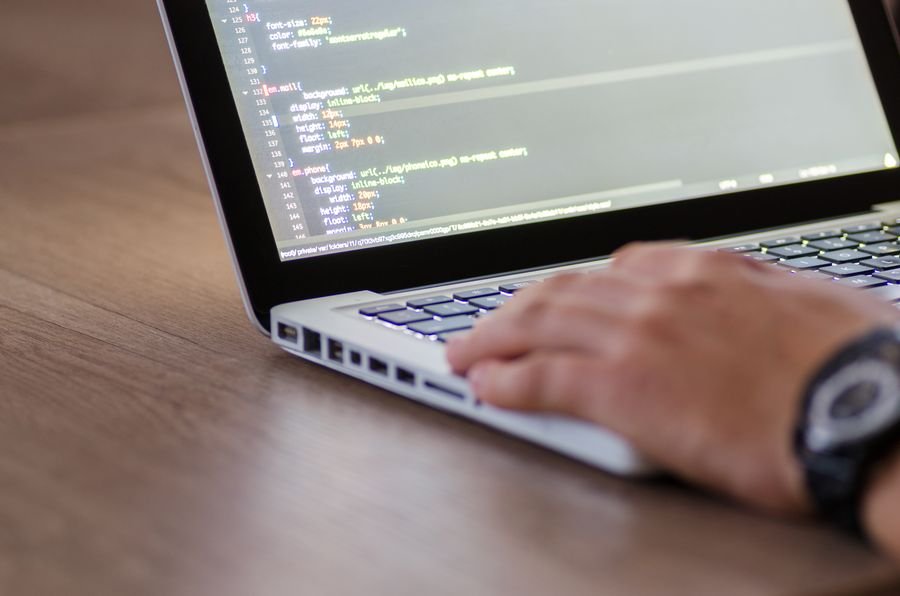 A developer writing code on a laptop