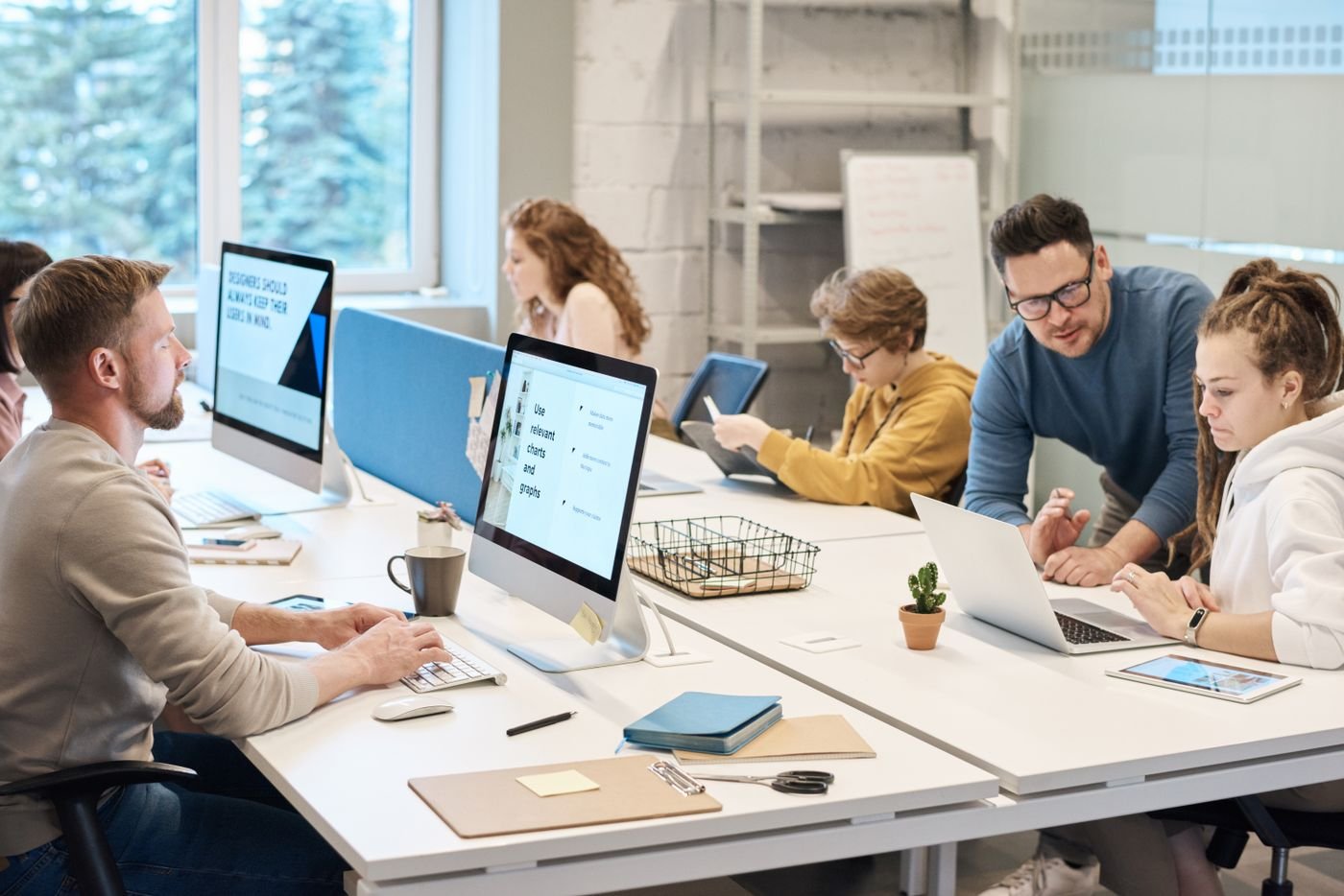 A creative team collaborating around laptops in a modern studio